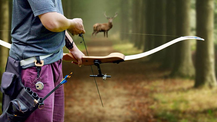 A bow Hunter aiming at a White tail buck against